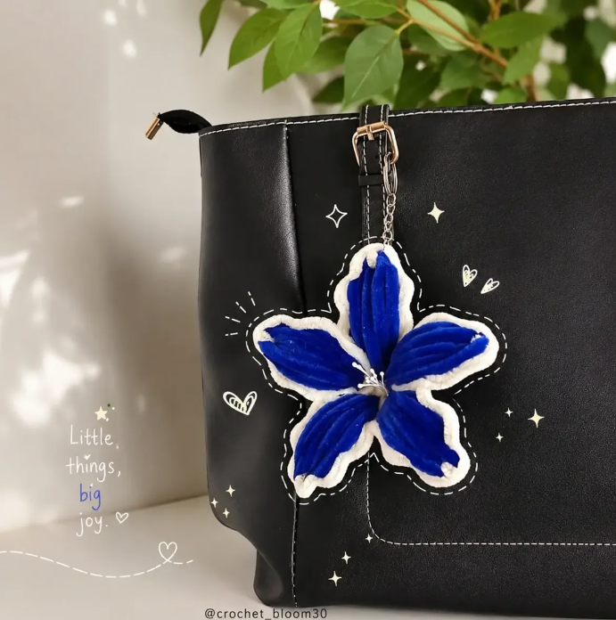 Blue crochet flower keychain on a black bag
